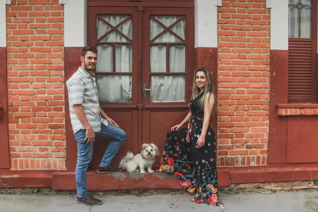 A man and a woman posing in front of a door with a dog