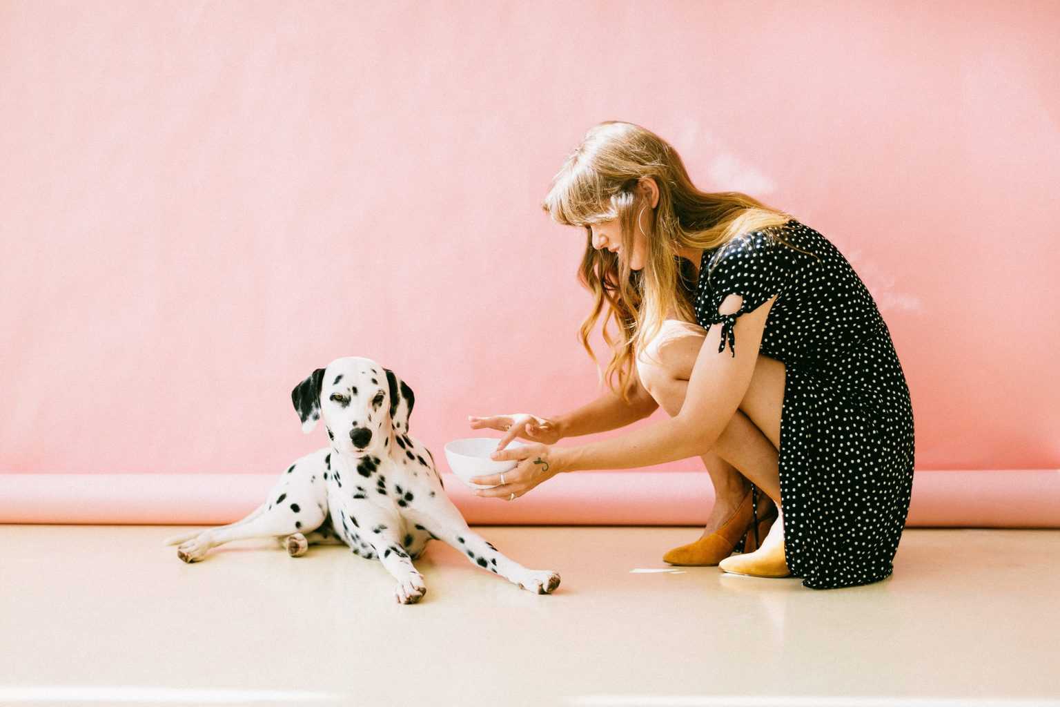 Woman holding a bowl while trying to feed her Dalmatian